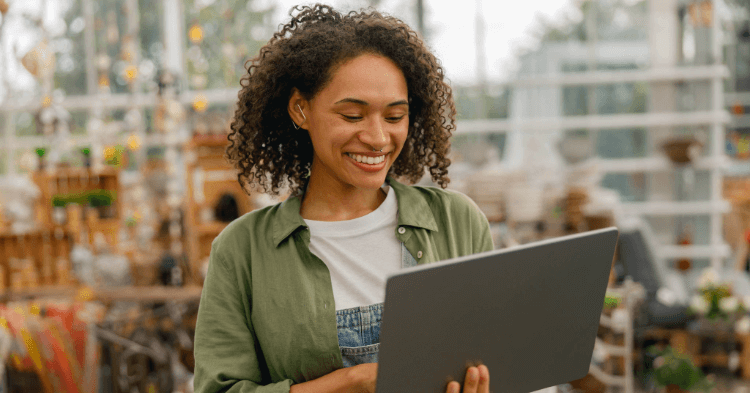 Woman in a plant shop smiling at her tablet.