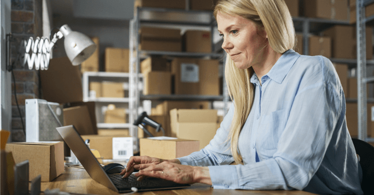 Woman looks at laptop, seated.