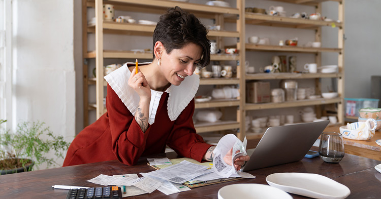 Business women holding pencil and reviewing documents in her shop