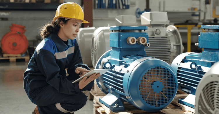 Woman in a hard hat inspecting a piece of industrial business equipment