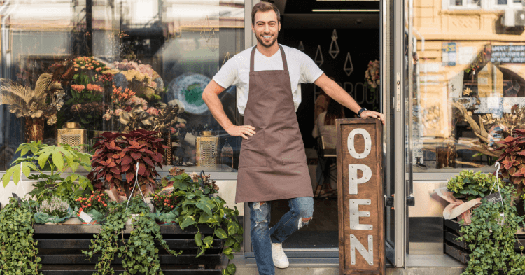 Small business owner standing outside the flower shop with an open sign