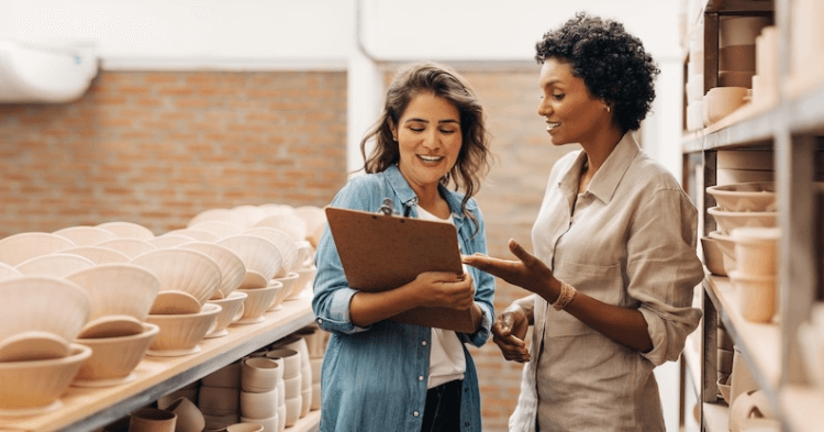 Two business owners looking at a clip board in their pottery shop